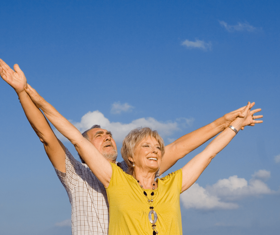 Elderly couple holding their hands up in the air